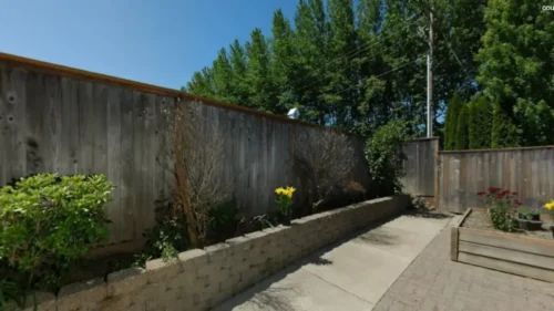 Private courtyard at Bridge Creek with garden beds, flowers, and wooden fencing